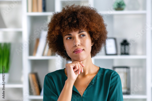 Thoughtful Black businesswoman looking away with pensive face, dreaming, thinking over project tasks, problem solving