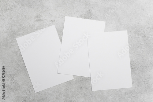 Three blank white cards on grey concrete background, ideal for greeting, invitation or flyer designs presentation, wedding cards, or minimalist stationery