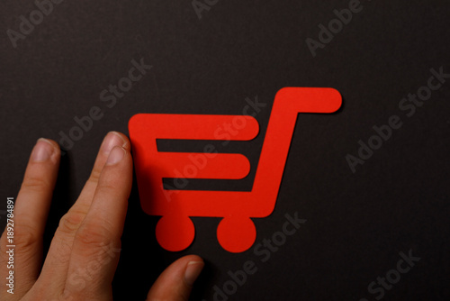 Hand holding a red shopping...