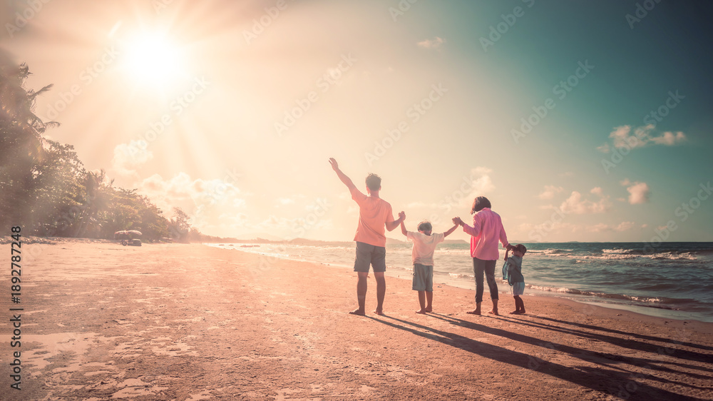 Fototapeta premium Happy family on the beach against blue sea and sky background at sunset. Holiday and summer travel concept
