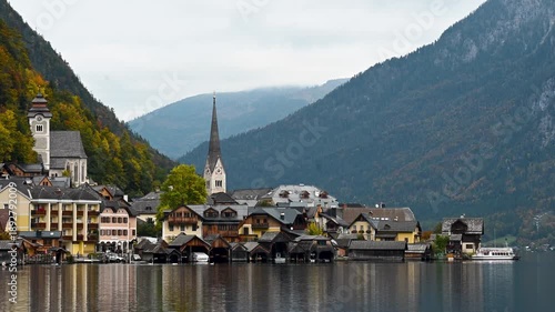 Hallstatt, Austria -  October 12, 2025: Sensic view of Hallstatt village with traditional alpine houses, church tower and mountains reflected in the lake. Scenic autumn landscape in Austria, popular t