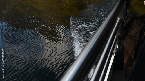 Touristic Boat moving on calm lake creating waves and wake