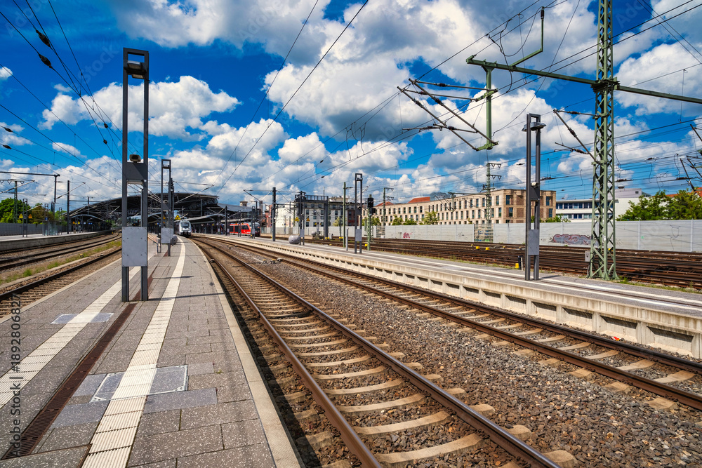 Naklejka premium Expansive platform beneath cloudy sky, linear perspective conveying motion at railway transit point