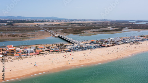This aerial scene captures praia de Faro and new bridge in Portugal with the sandy beach, clear water, and a bridge connecting the land over a tranquil estuary