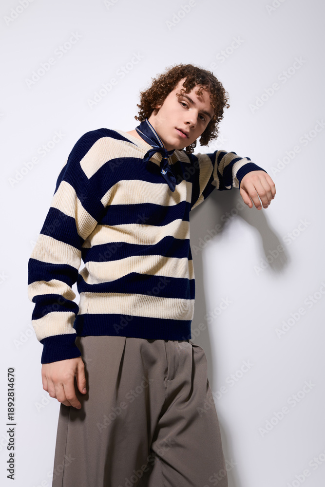 Fototapeta premium Stylish teenager poses confidently in trendy outfit against a simple backdrop
