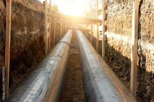 Industrial site showcasing the installation of pre-insulated steel pipelines in a trench. Ideal for: district heating project reports, energy efficiency articles, and utility maintenance news.