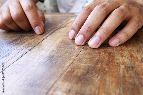 A person's hands resting on a wooden table