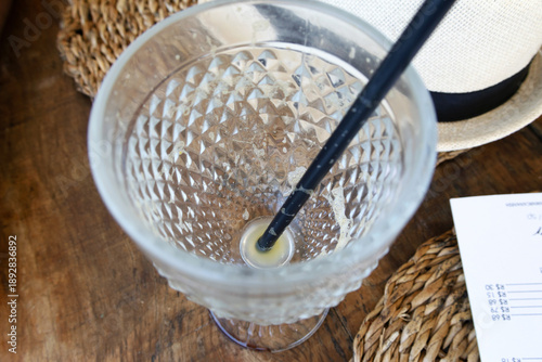An empty glass with a black straw inside, containing traces of a yellow liquid that suggests orange juice, was photographed from above