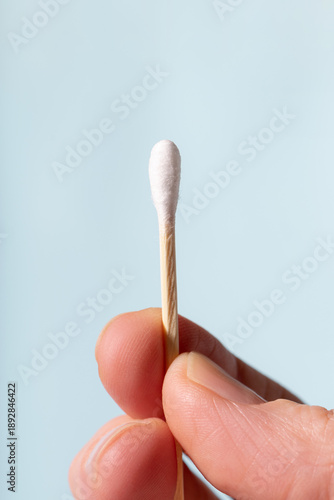 Hand holding cotton swab for ear cleaning and hygiene
