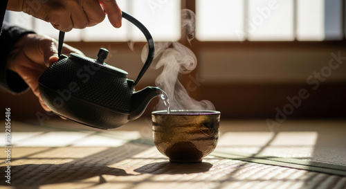 A hand pours steaming tea from a traditional kettle into a beautifully crafted cup, set against a serene backdrop of natural light.