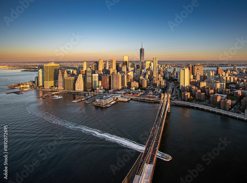 Photos Lower Manhattan at sunset, with the historic Brooklyn Bridge leading the eye toward a dense forest of skyscrapers