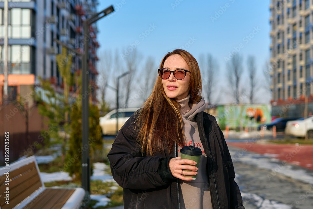 Fototapeta premium girl walks down the street with coffee in the spring