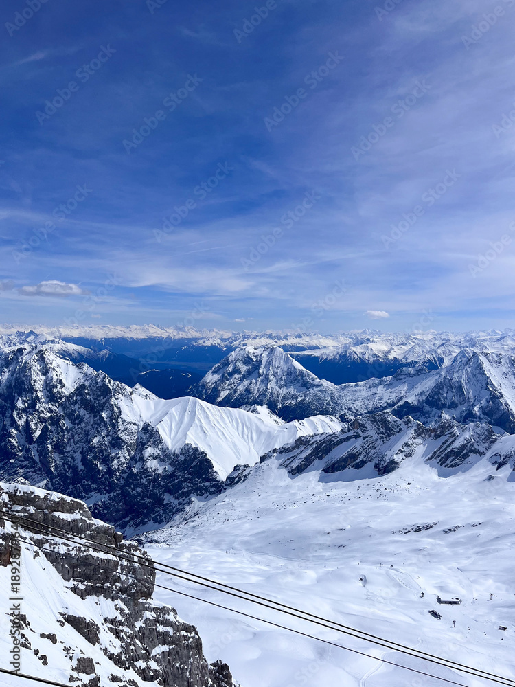 Fototapeta premium Zugspitze peak, the highest peak of Germany near Garmisch Partenkirchen. A view from Zugspitze mountain peak station. Snow landscape in April. Zugspitze Ski Resort. Winter in the Bavarian Alps. Hiking