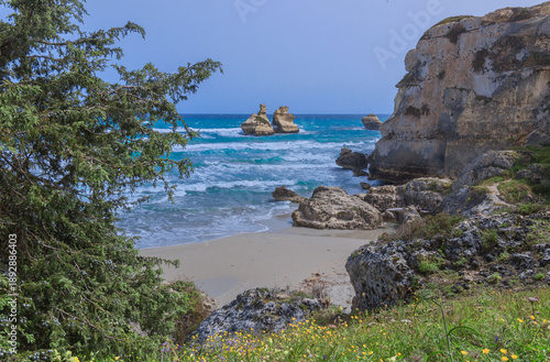 Glimpse of the sea stack Due Sorelle on the Torre dell'Orso beach in Apulia, Italy.