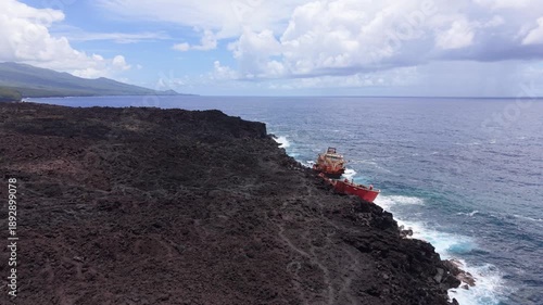 Drone approaching stranded tanker along volcanic lava coast, Chemin des Laves, Reunion Island