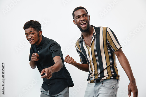 Fotografi Two young black men with dark skin posing and smiling on white background
