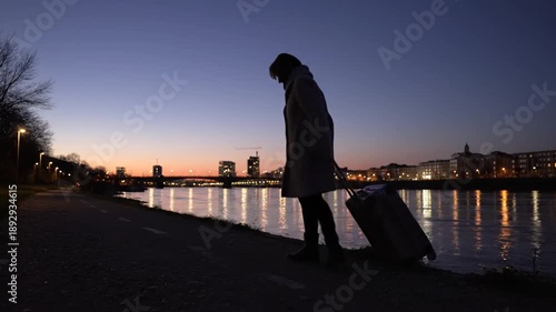 Silhouette Traveler Walking Along Urban Waterfront At Dusk.