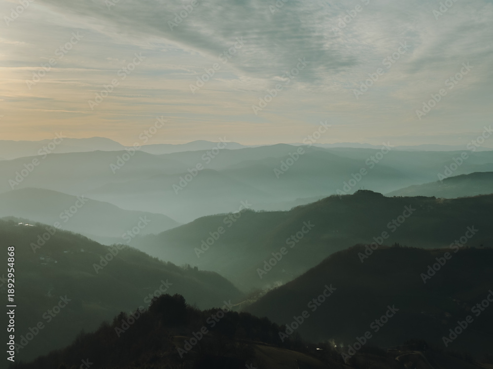 Obraz premium Layered mountain ridges in Serbia fading into mist. Soft light, atmospheric perspective and endless hills create a calm and minimalist natural background.