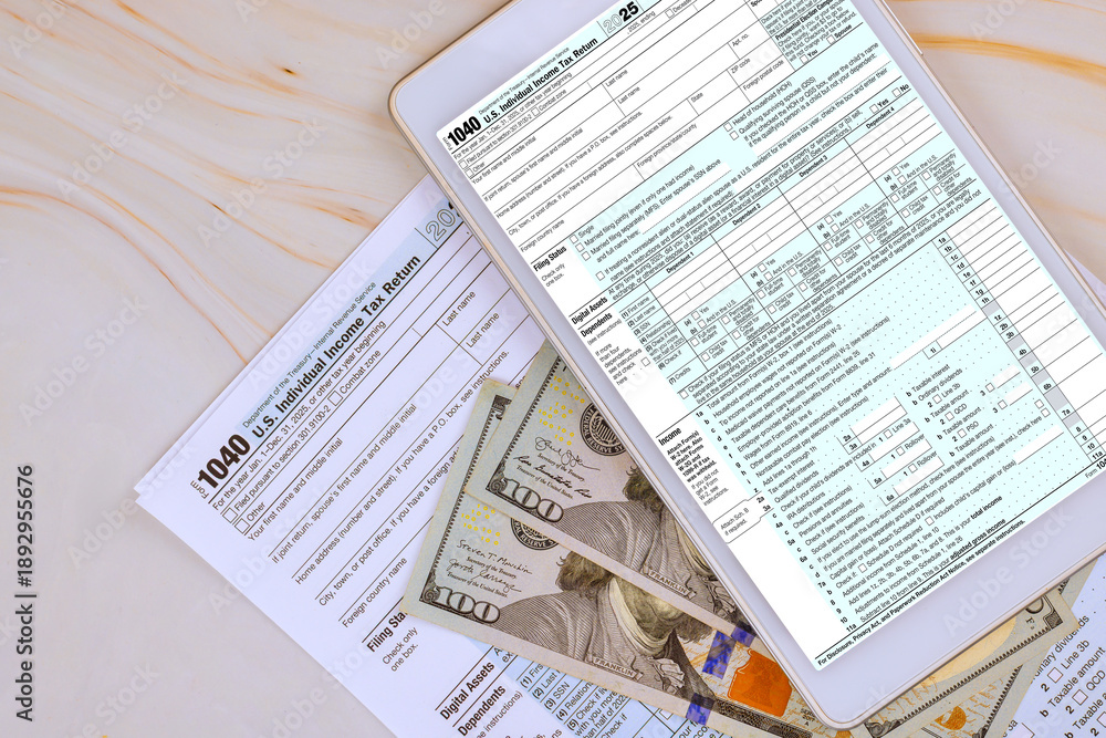 Obraz premium Digital tablet displays tax 1040 forms while US cash banknote is scattered on table with other tax documents.