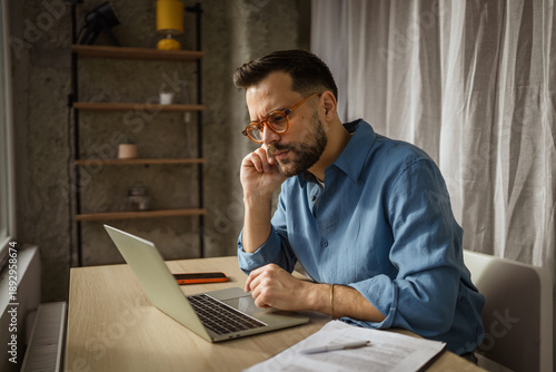 Fotografía Young man concentrating on laptop working from home office