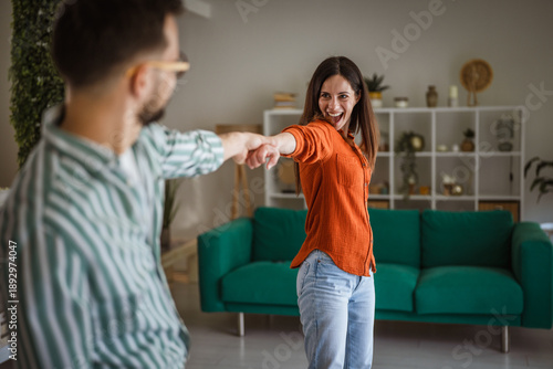 Happy young couple dancing at home enjoying time together