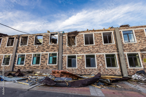 Canvas-taulu Two story brick building with patterned facade shows partial roof collapse, broken windows, and scattered debris damage suggests recent destructive event