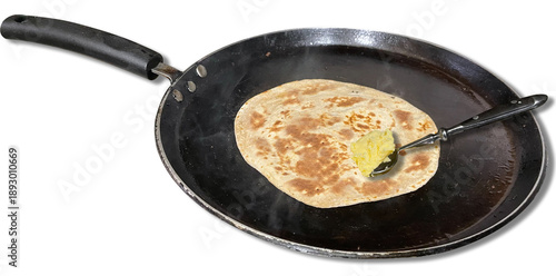 Chapati cooking on a fry pan with a scoop of butter on it. Indian Roti.