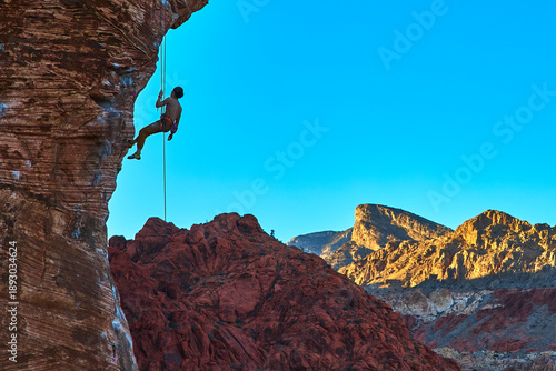 Foto Rock Climber Scaling Red Rock Canyon Wall with Calico Hills and Turtlehead Peak