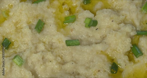 Close-up of the texture of Turnip Skordalia. Creamy Greek dip made of turnips, garlic, and olive oil garnished with chopped scallions and olive oil. 