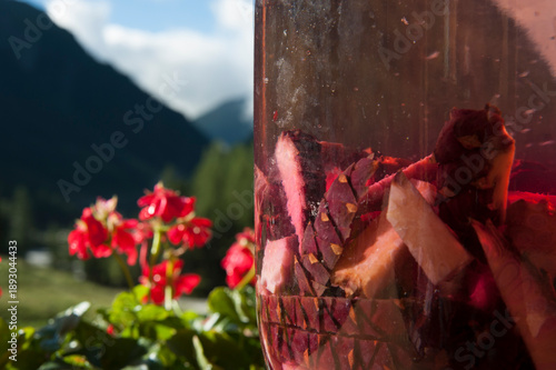 Close-up of Swiss stone pine cone infusion in glass jar, homemade Tyrolean Zirbala schnapps in sunlight with alpine bokeh