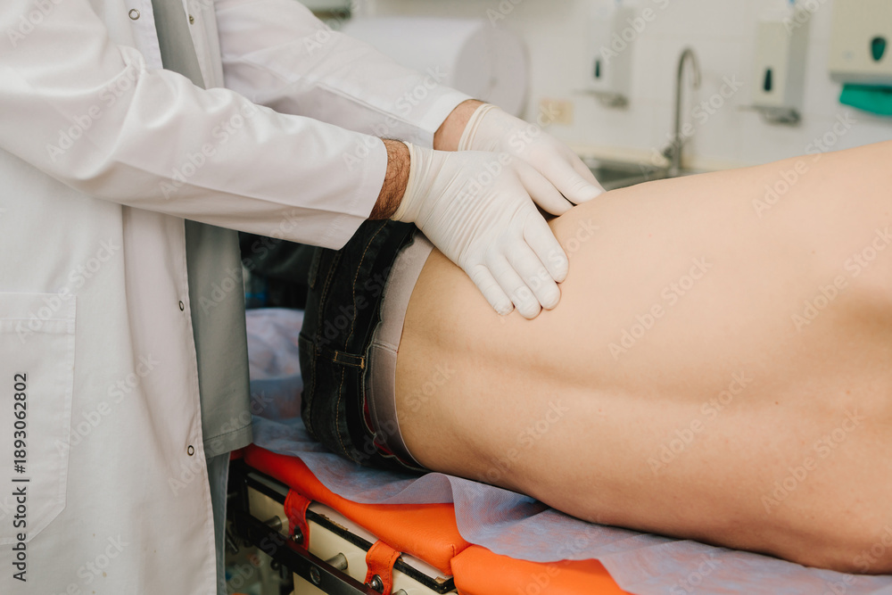 Obraz premium Urologist palpates kidneys of male patient lying on back to check pain or size.