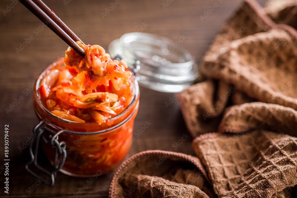 Fototapeta premium Fermented cabbage. Kimchi. Korean food in jar on wooden table.