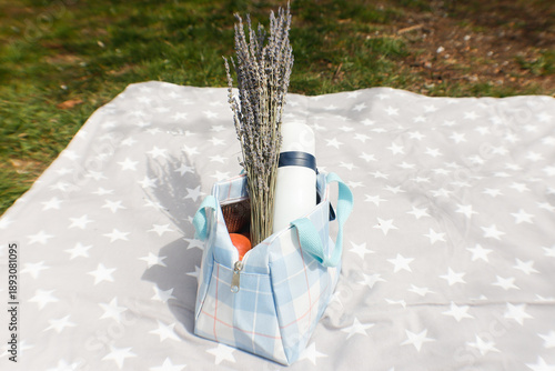 Picnic basket with flowers, thermos and fruits