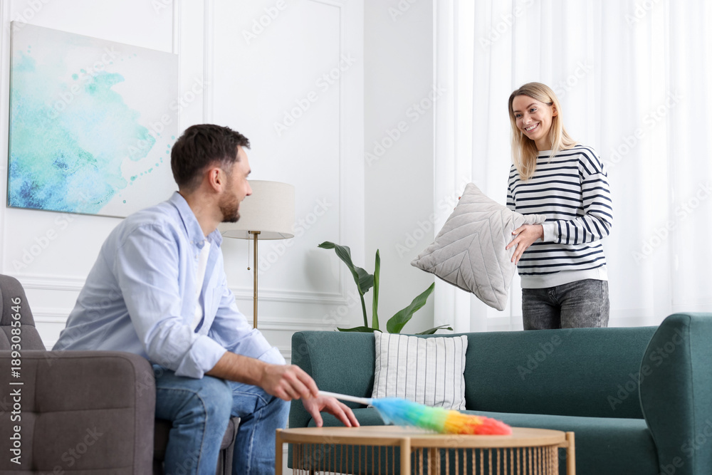 Obraz premium Couple tidying up living room together. Domestic chores