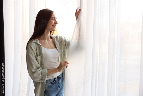 Happy woman near window with beautiful curtains at home Free Download Happy woman near window with beautiful curtains at home - GFXLoad
