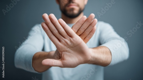 Man using crossed hands to signal refusal in a neutral setting during the day, highlighting body language and communication without speaking in a clear manner