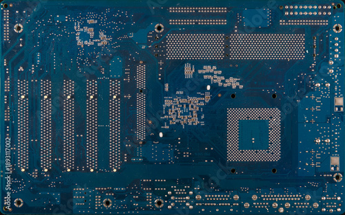 Blue printed circuit board back side with solder points and traces, electronics motherboard texture background