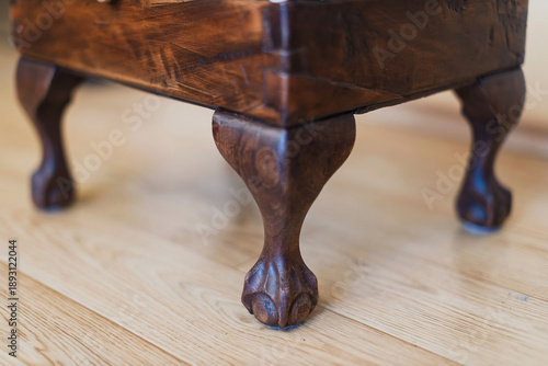 Ornate wooden furniture legs sit on a polished wooden floor.