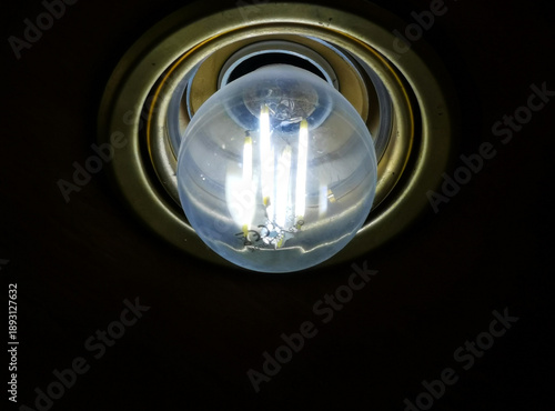 Lampadina led accesa con filamenti incandescenti in portalampade color ottone