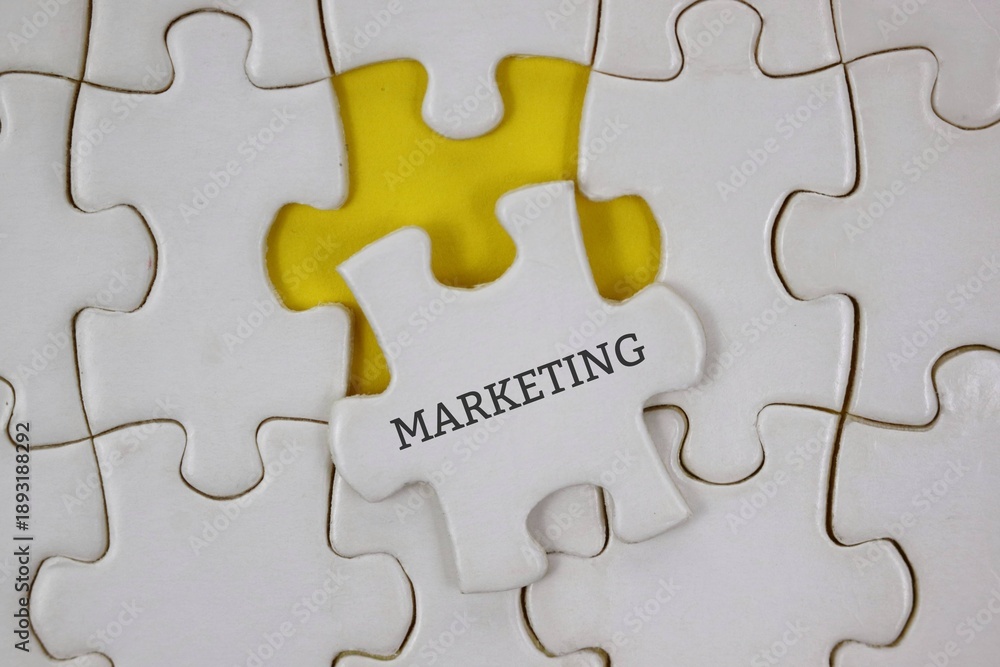 Fototapeta premium white puzzle piece labeled MARKETING sits among others on a yellow background, symbolizing strategic thinking and collaboration.