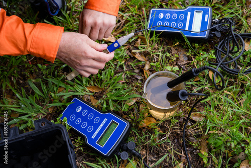 A field technician taking and testing a water sample with equipment - horizontal