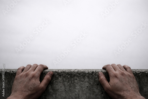 Reaching Out: A powerful image shows a pair of hands gripping the edge of a wall, creating an image of determination and resilience.