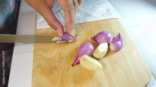 Close up of a mother's hands cutting red onions on a wooden cutting board