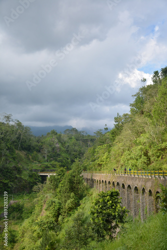 Plunyon Kalikuning is a popular riverside park featuring a historic bridge, hiking trails, and panoramic views of the green hills and mountains