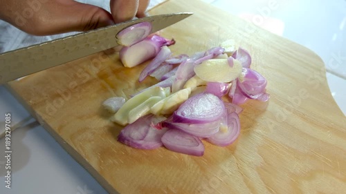 Close up of a mother's hands cutting red onions on a wooden cutting board