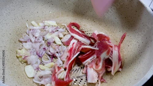 Close up of a mother's hand putting pieces of meat into stir-fried onions