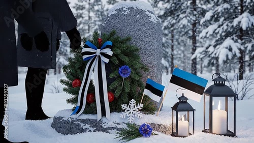 Estonian flag wreath on memorial stone in snowy forest with lanterns
