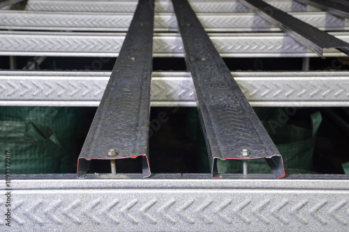 Detailed view of metallic building materials showing parallel steel channels bolted together to form a sturdy structural frame for a construction project under artificial night lighting.