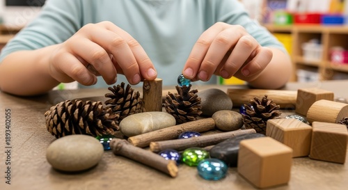 Young child manipulates natural loose parts for creative construction play on a tabletop