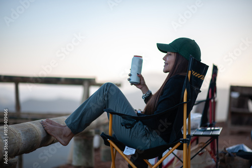 Fotografie A woman sits holding a canned drink in the middle of nature.
